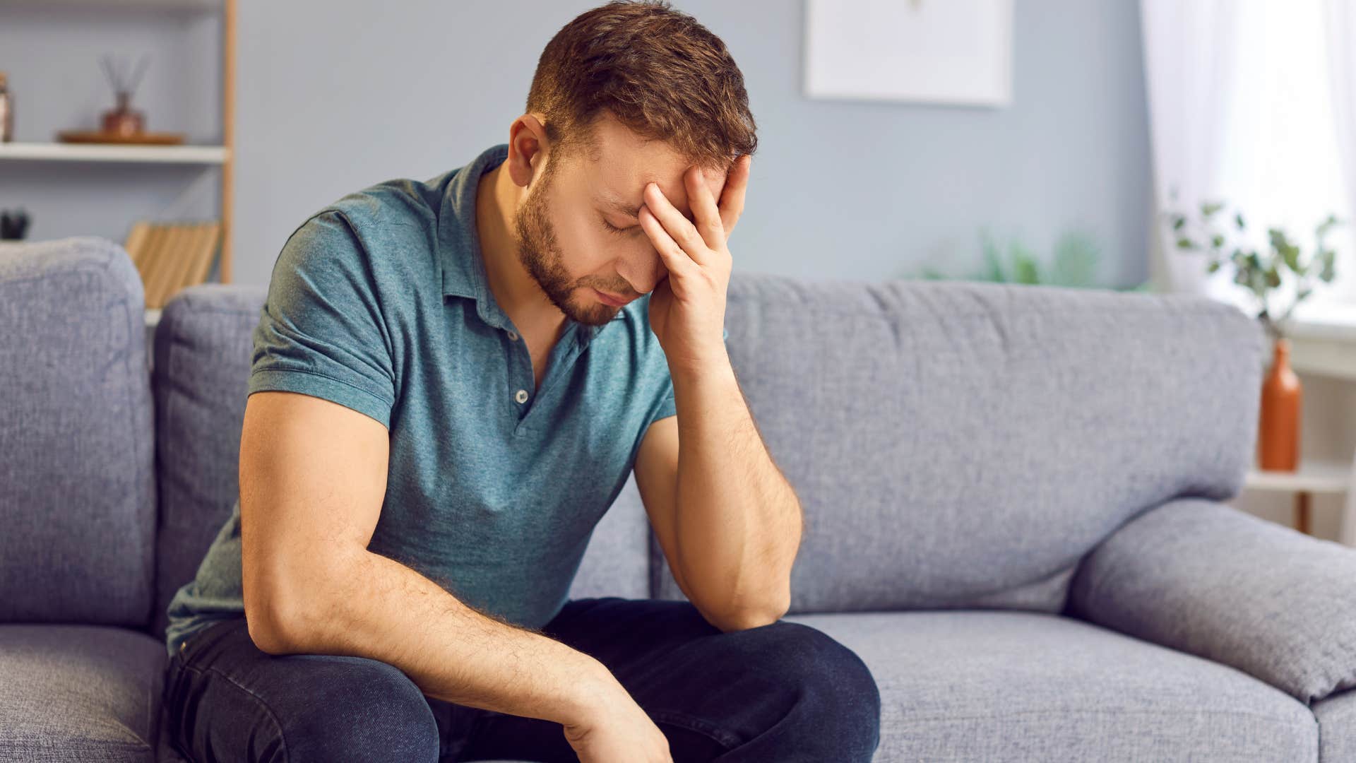 Man who feels guilty sitting on his couch at home.