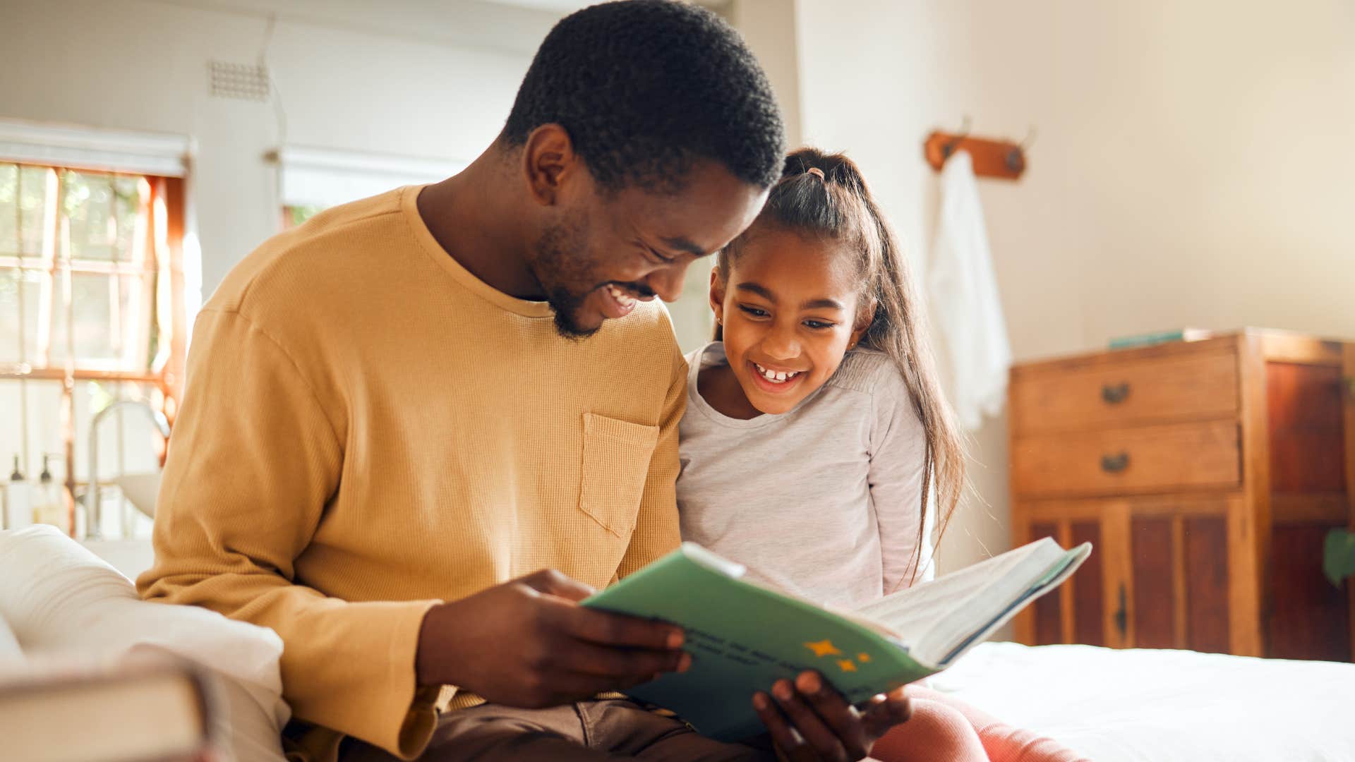 Man who's raising a family of their own reading with their daughter.