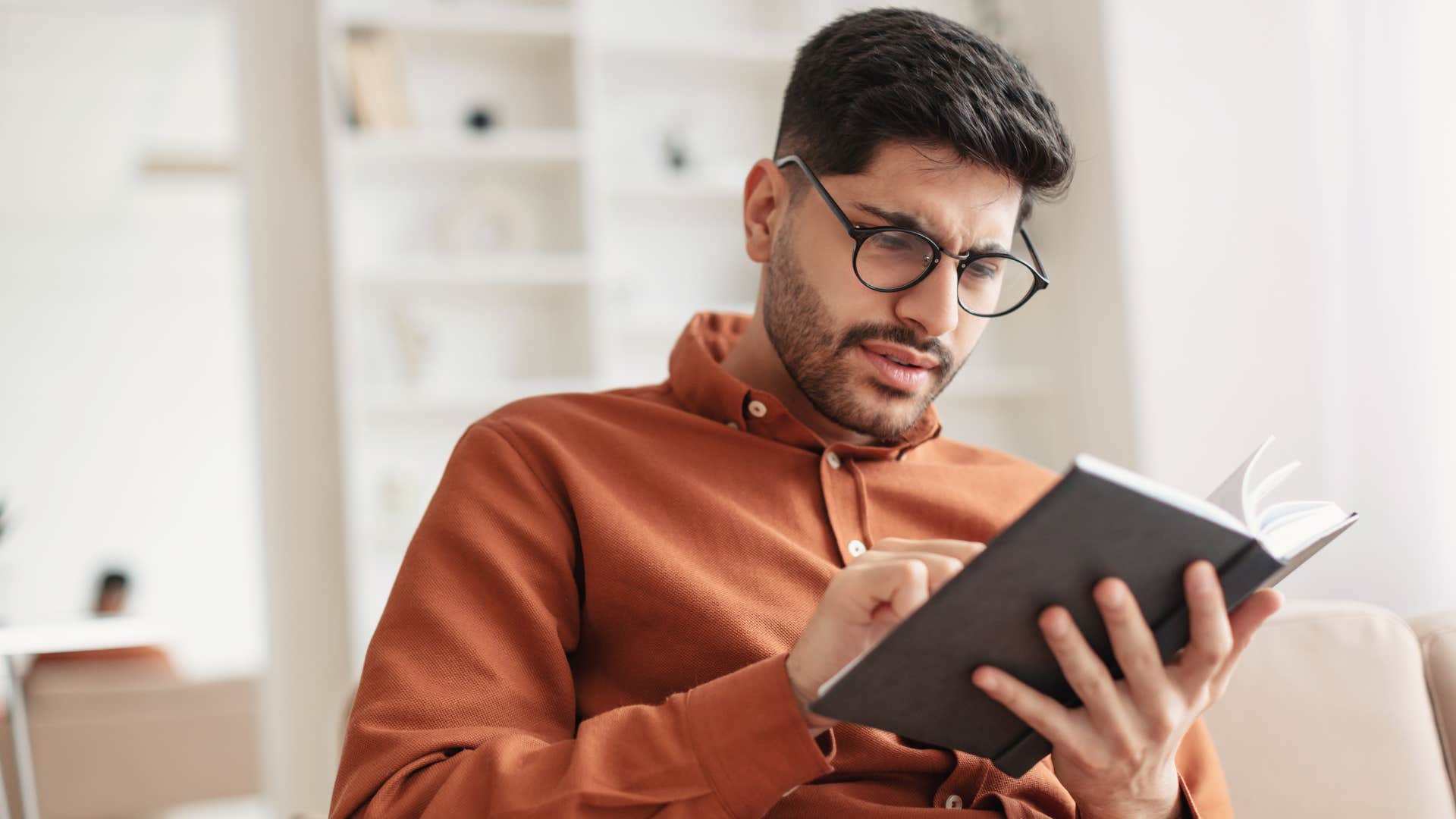 man reading antinomic literature in book looking confused