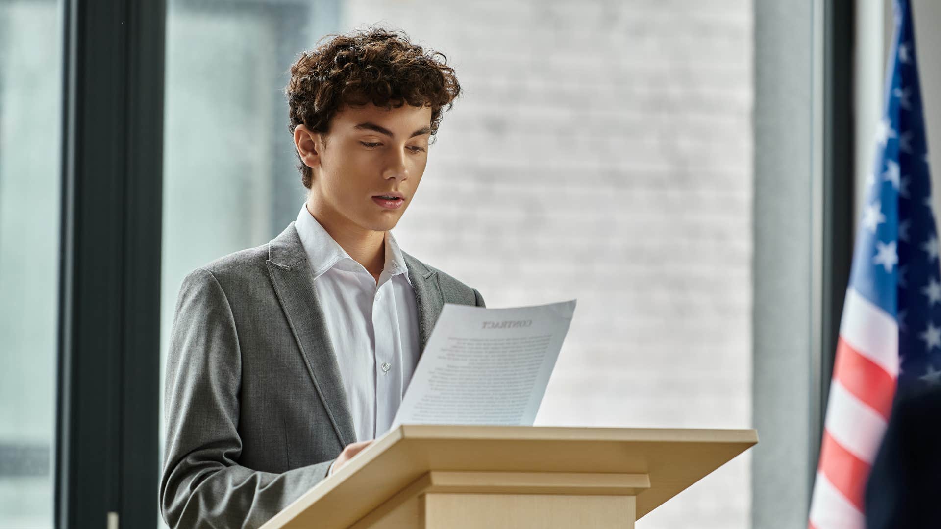young man giving a speech on egalitarianism at podium