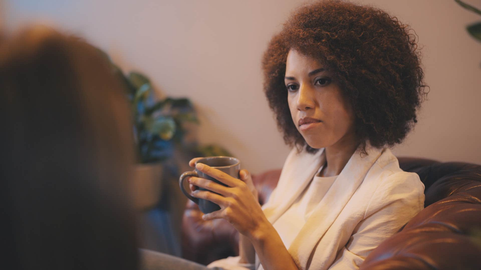 Woman who's started giving back-handed compliments looking at a friend.