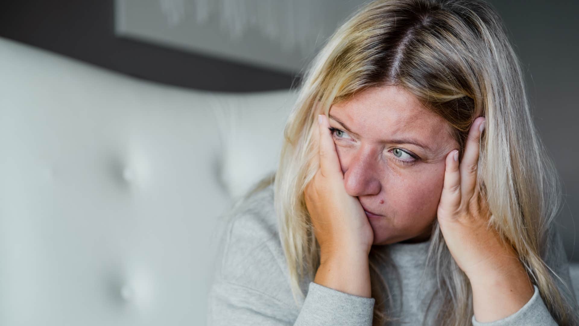 Woman who's always low energy sitting on her bed.