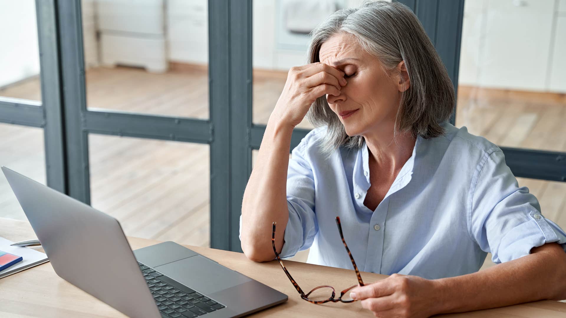 Woman with chronic headaches holding her head at work.