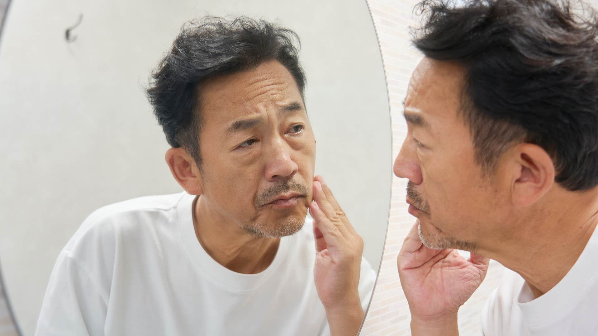 Man with dry skin looking in a mirror.