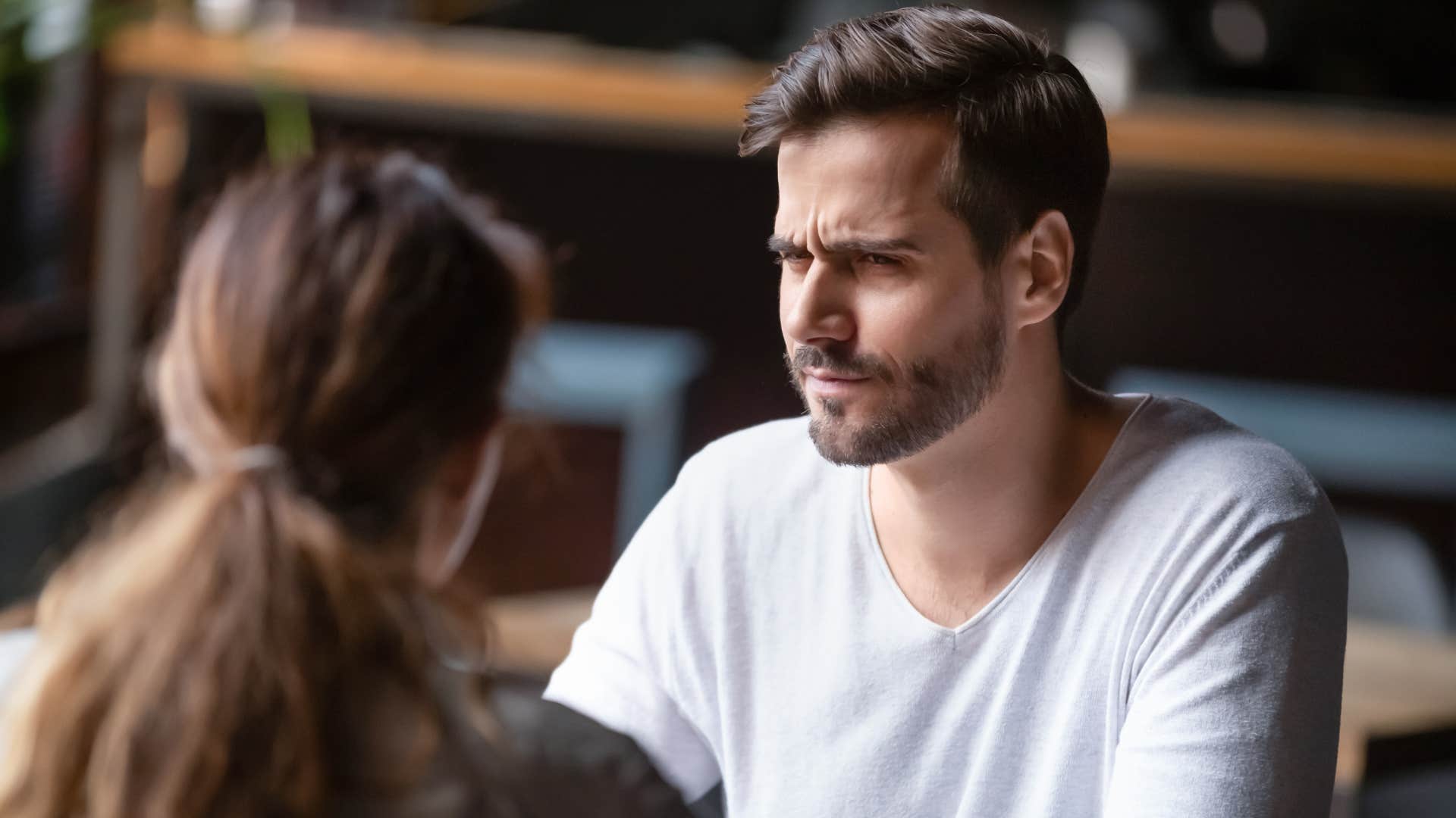 man in white shirt thinking that's not entirely correct while woman talks 