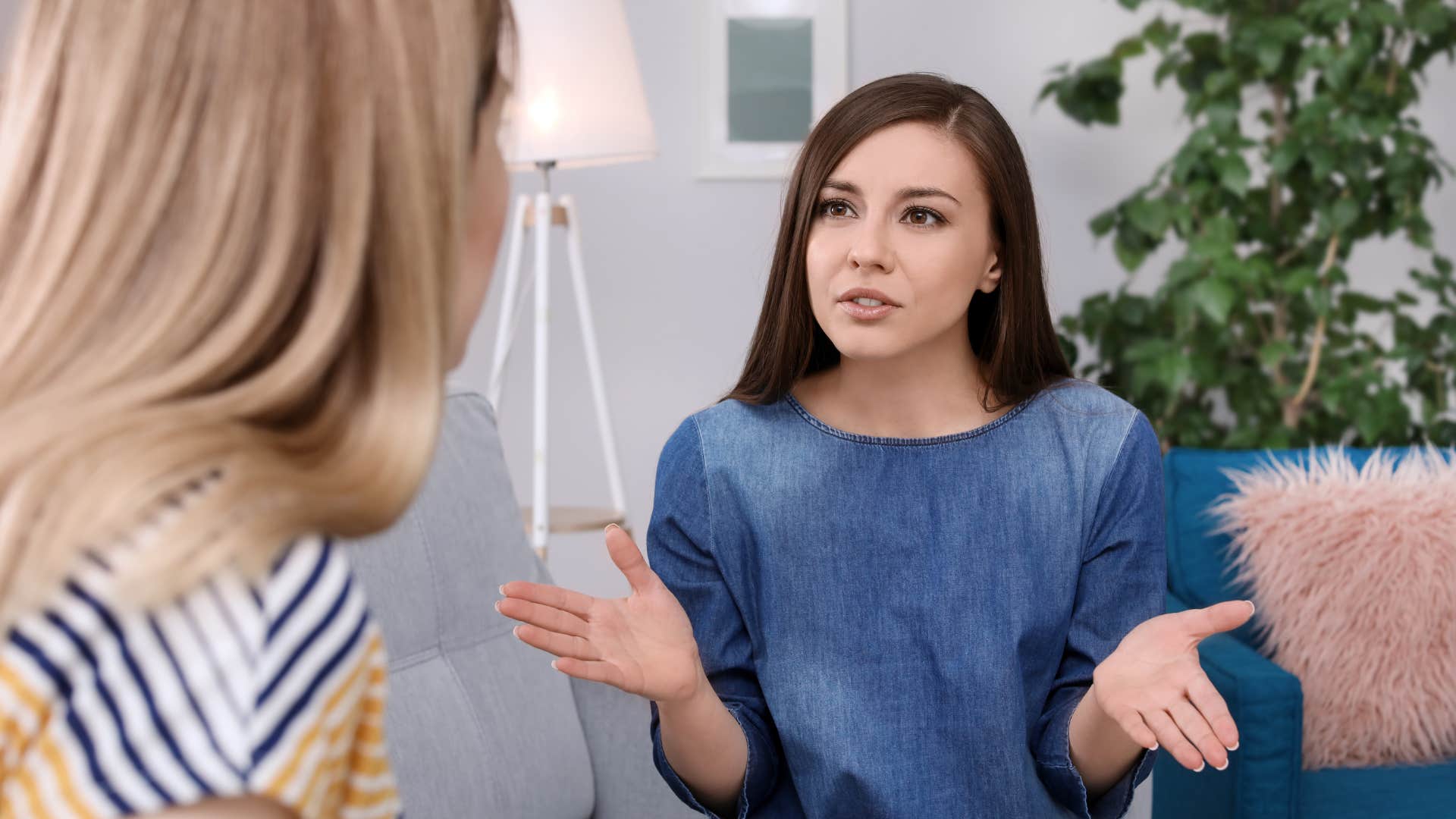 woman in denim dress projecting so hard as she talks to friend