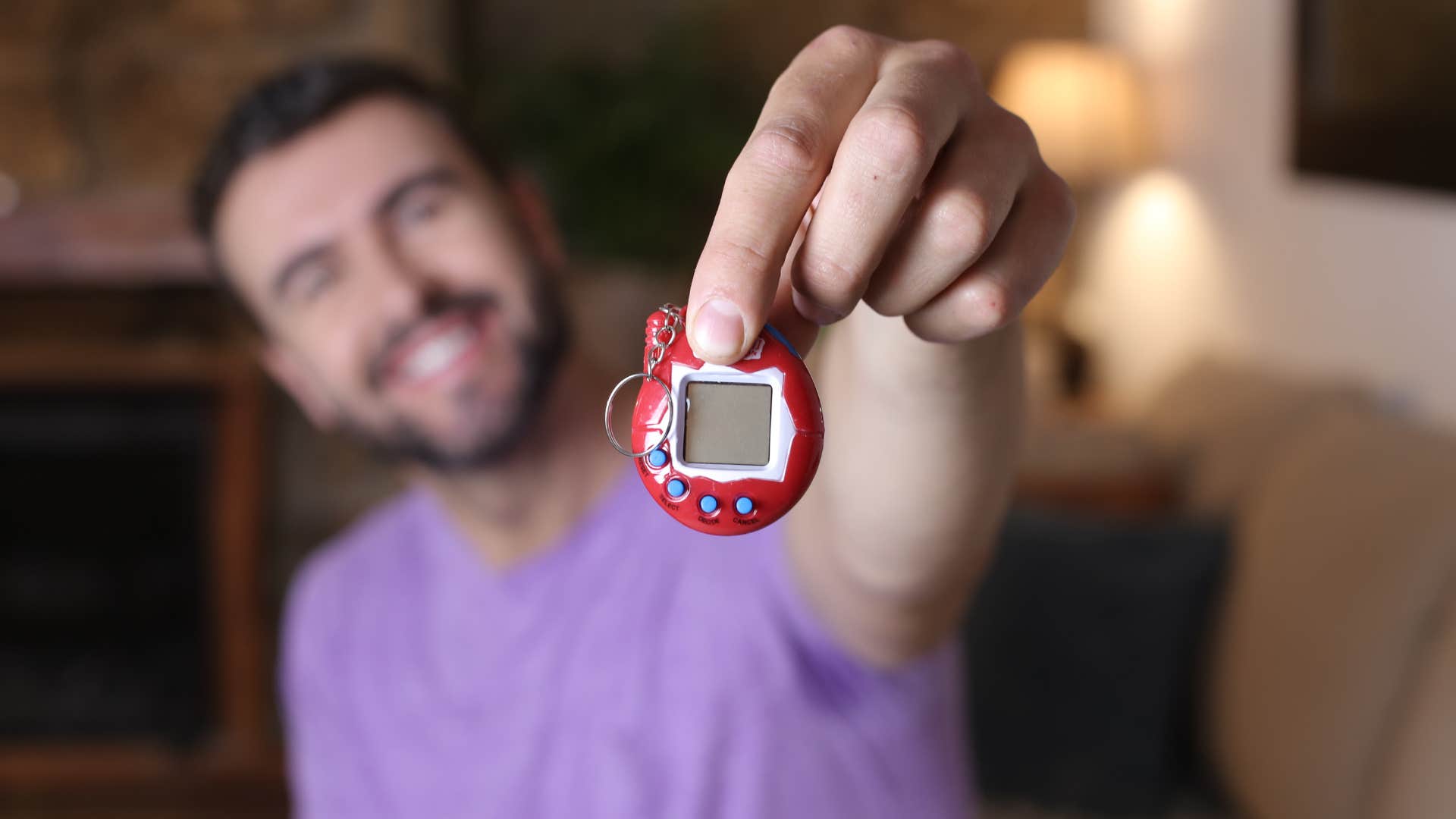 millennial man holding up tamagotchi