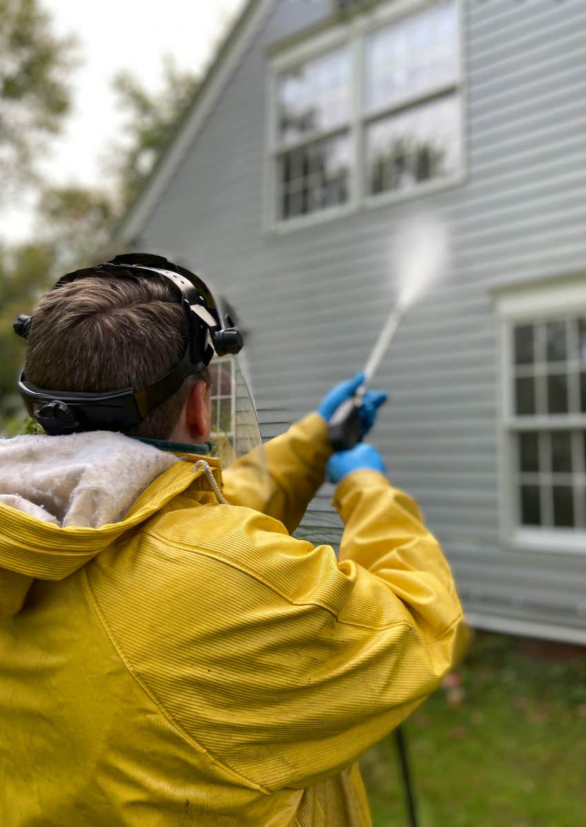 man pressure washing his house
