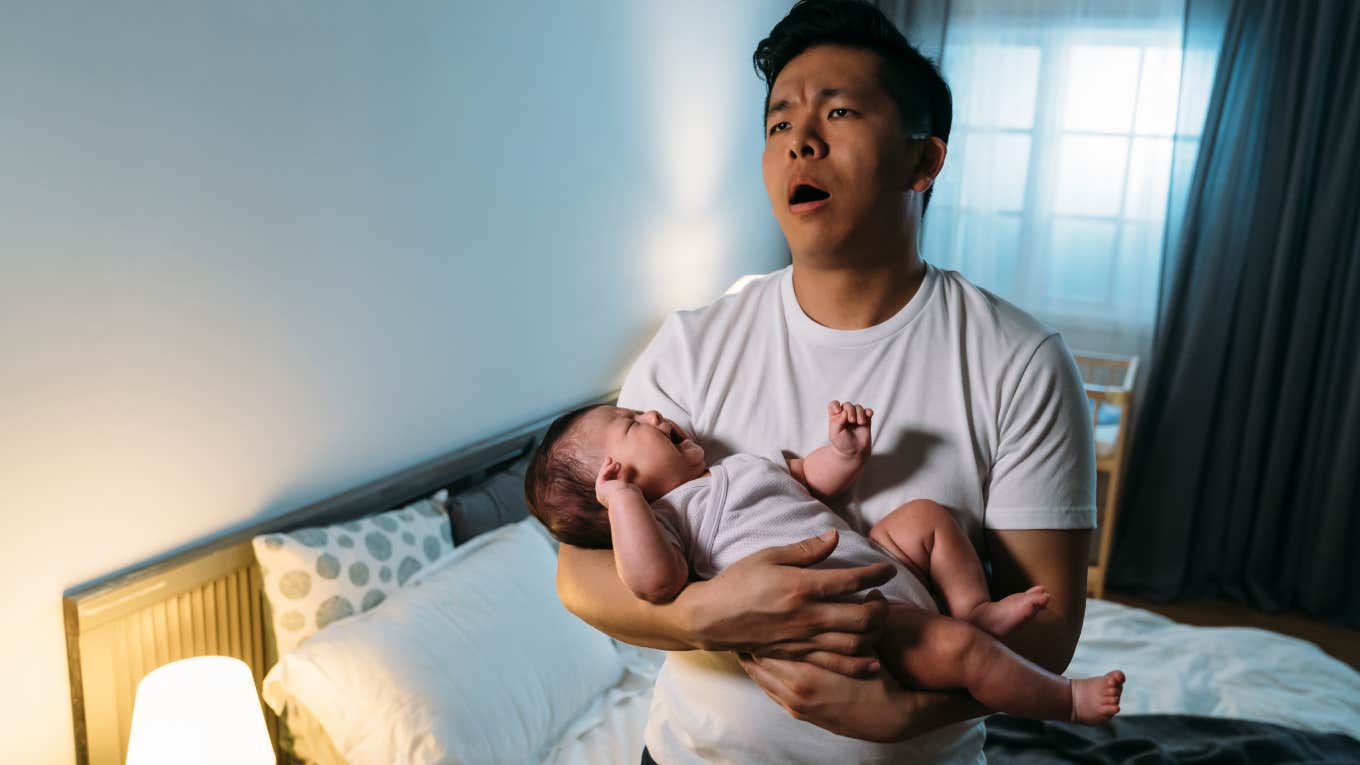 overwhelmed husband holding newborn baby