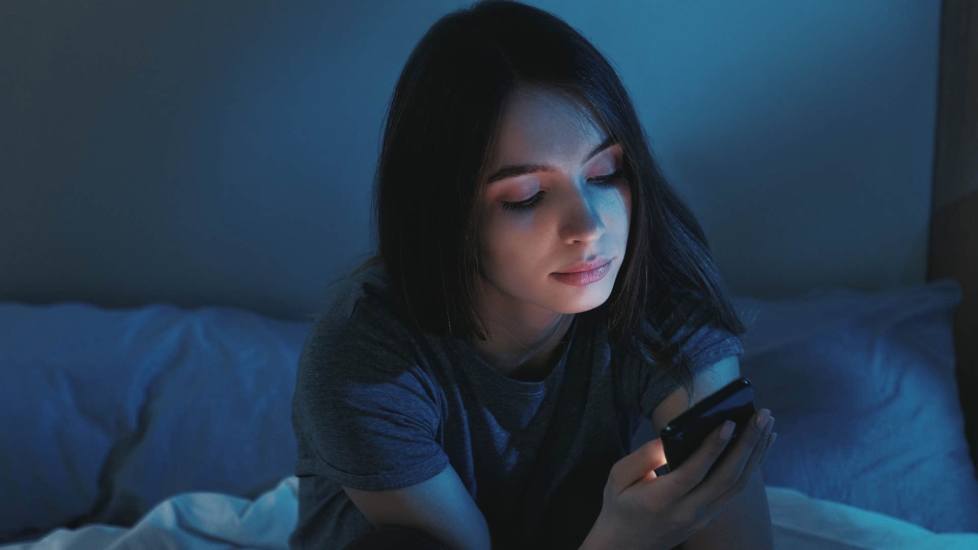 unhappy woman scrolling on her phone in the dark