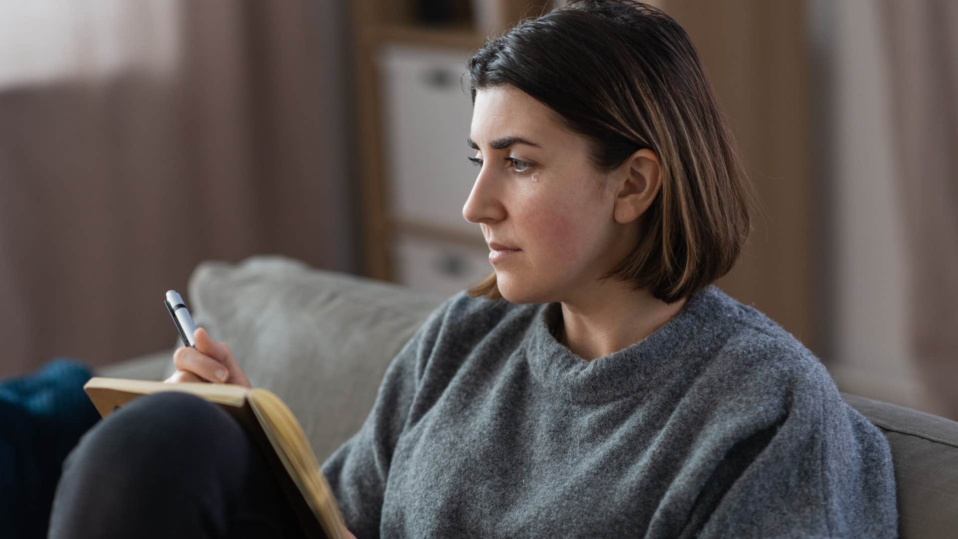 unhappy pensive woman writing in a secretive journal