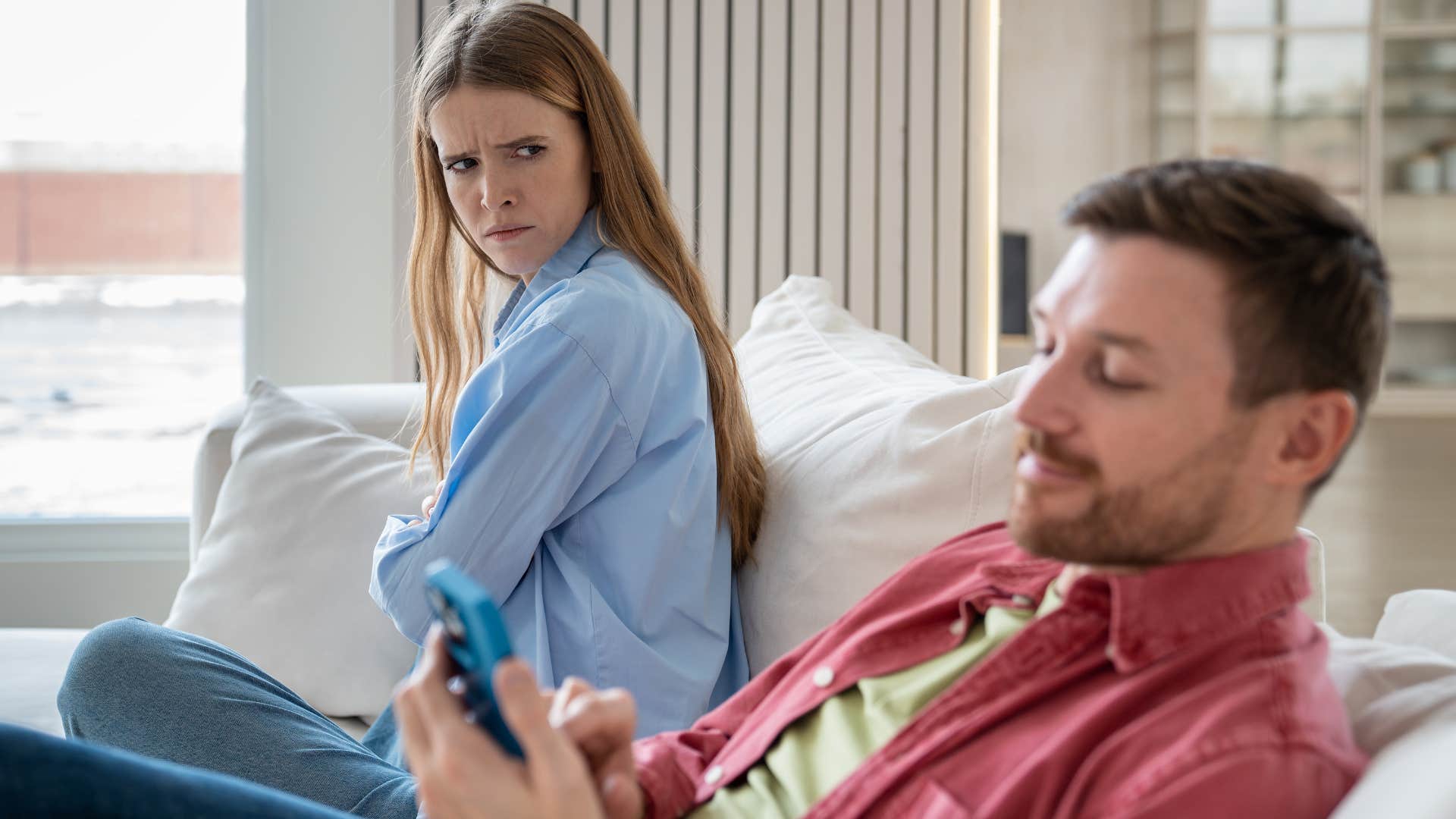 man distracted by phone acting uncaring towards wife