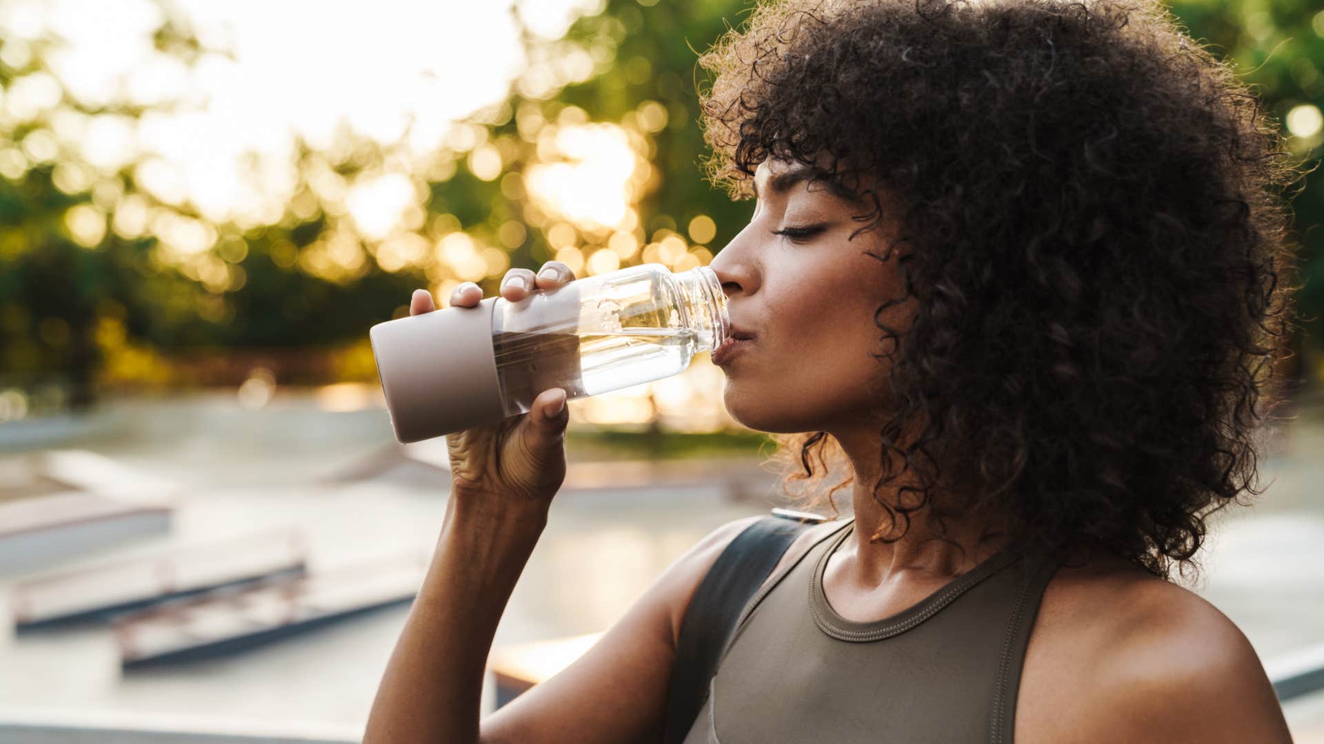 millennial woman drinking from glass luxury water bottle