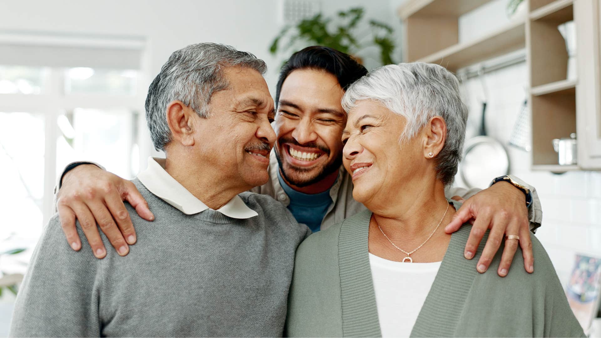 man smiling and hugging his parents making them proud