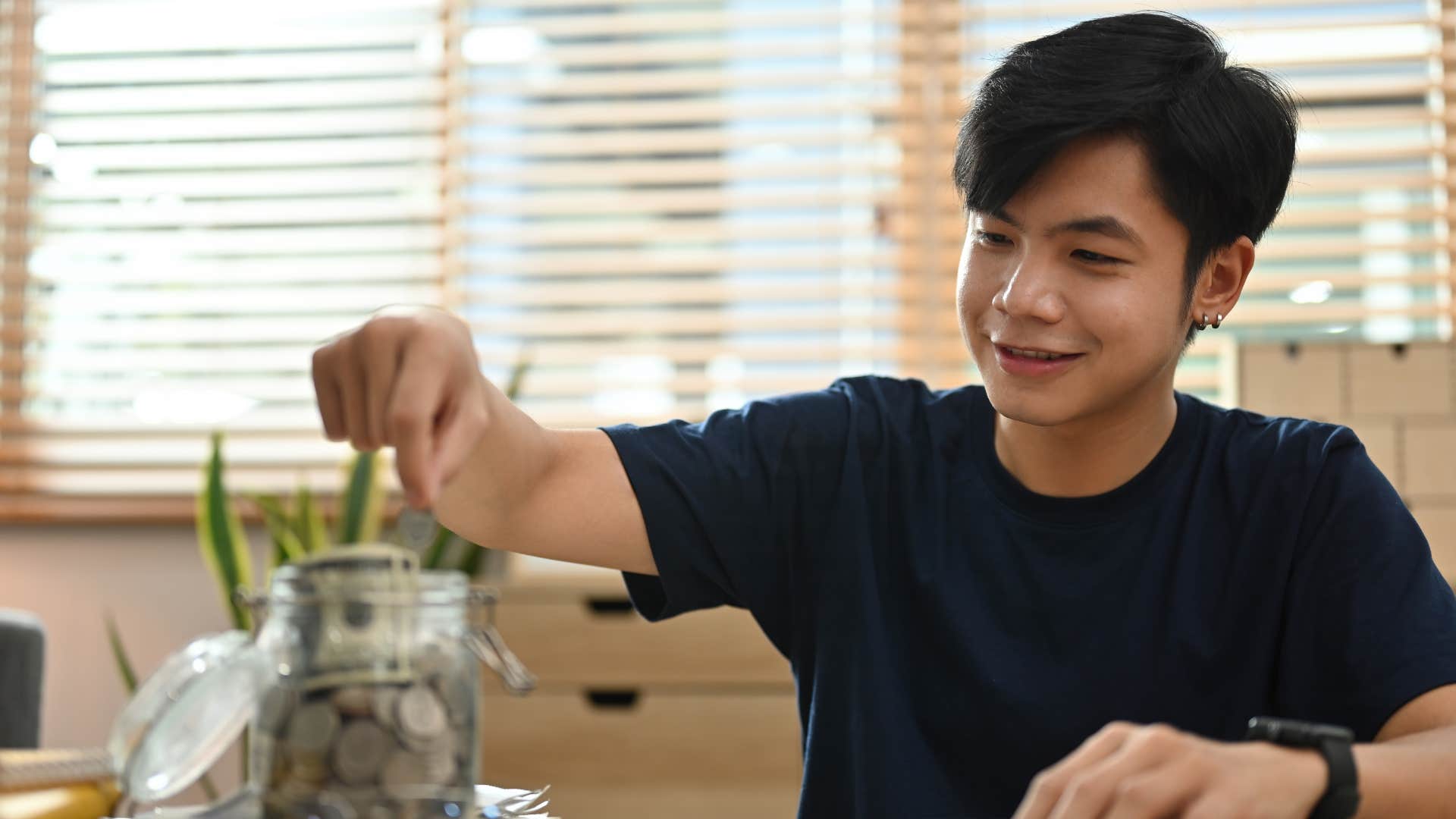 young man putting coin in jar