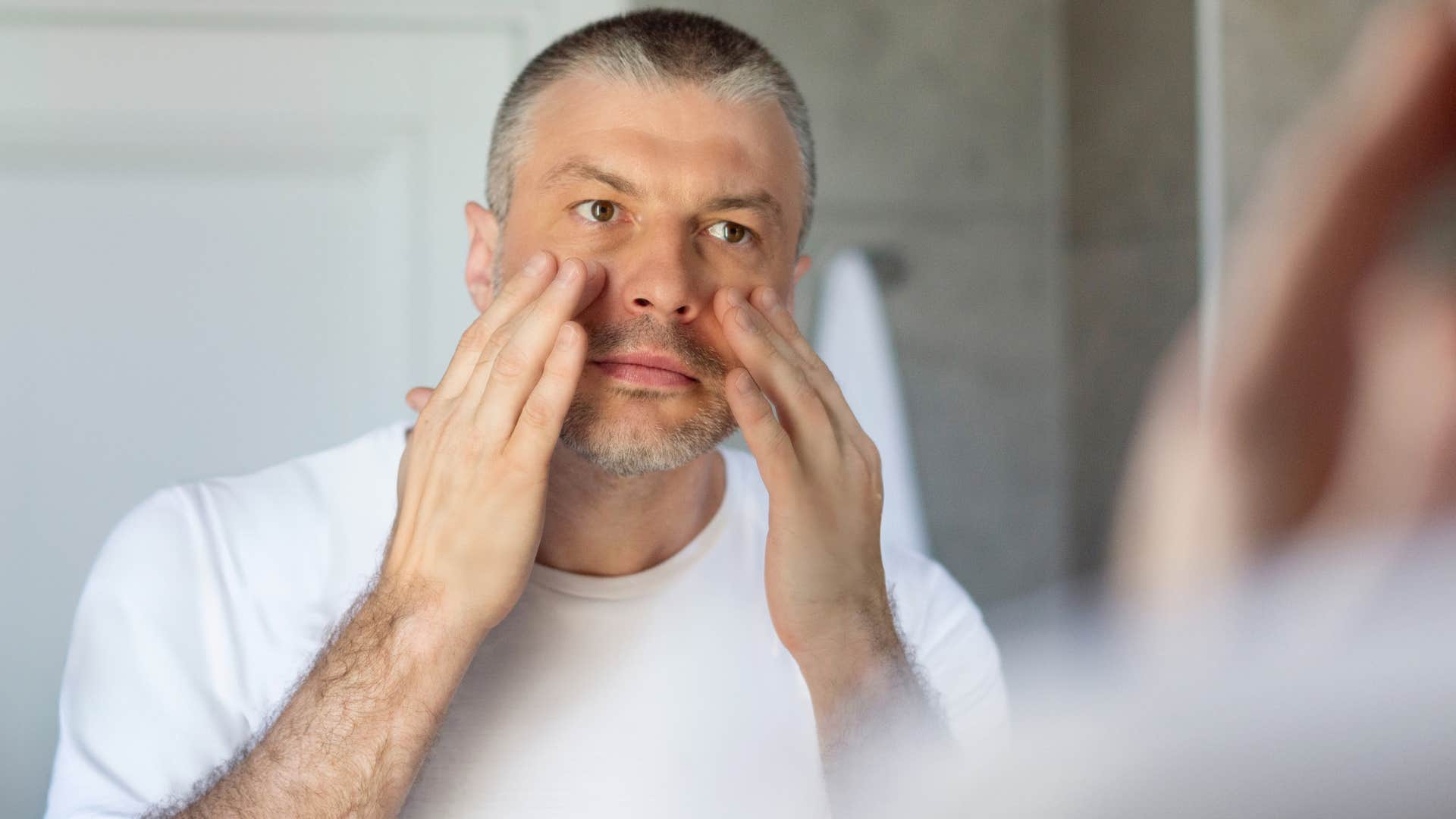 man with dark under eye circles looking in a mirror
