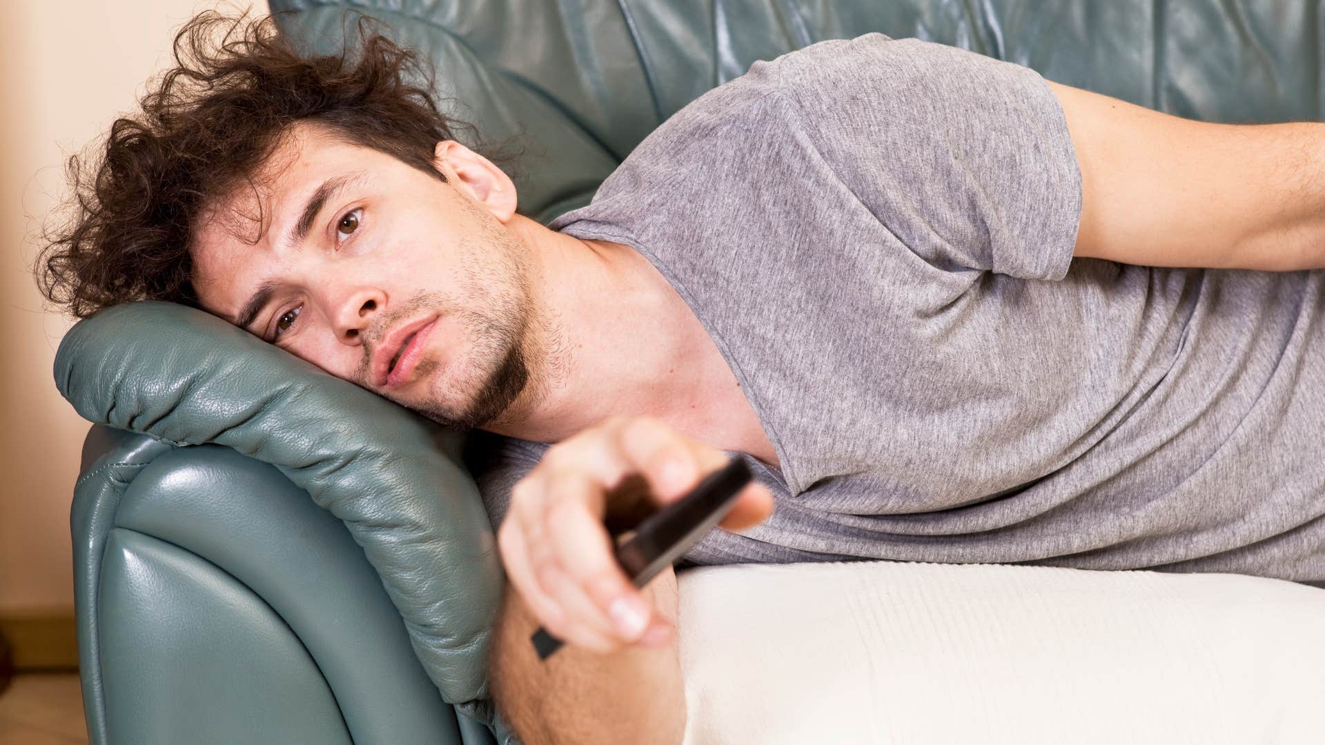man with unkempt hair laying on the couch