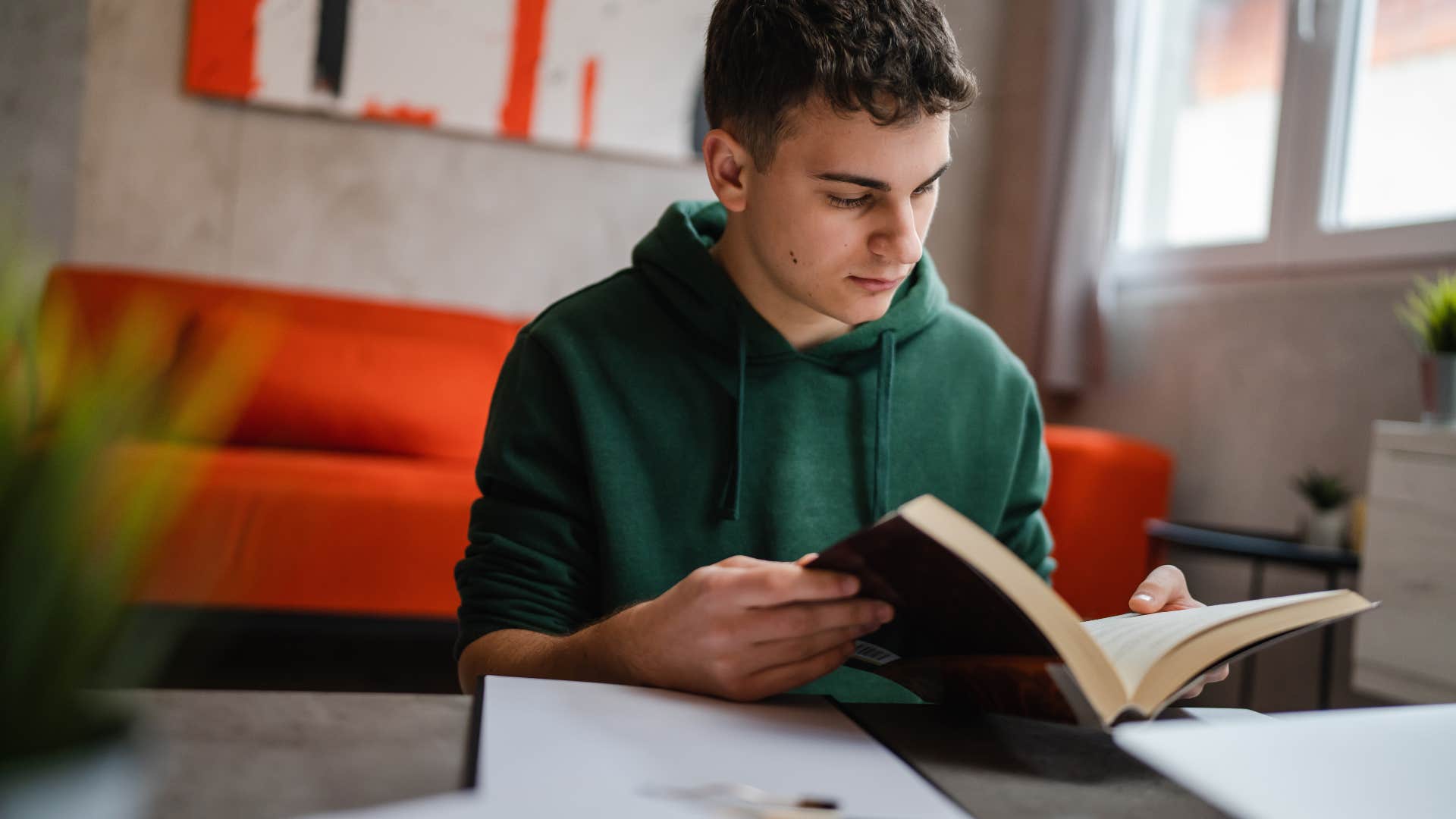 young man reading book in room