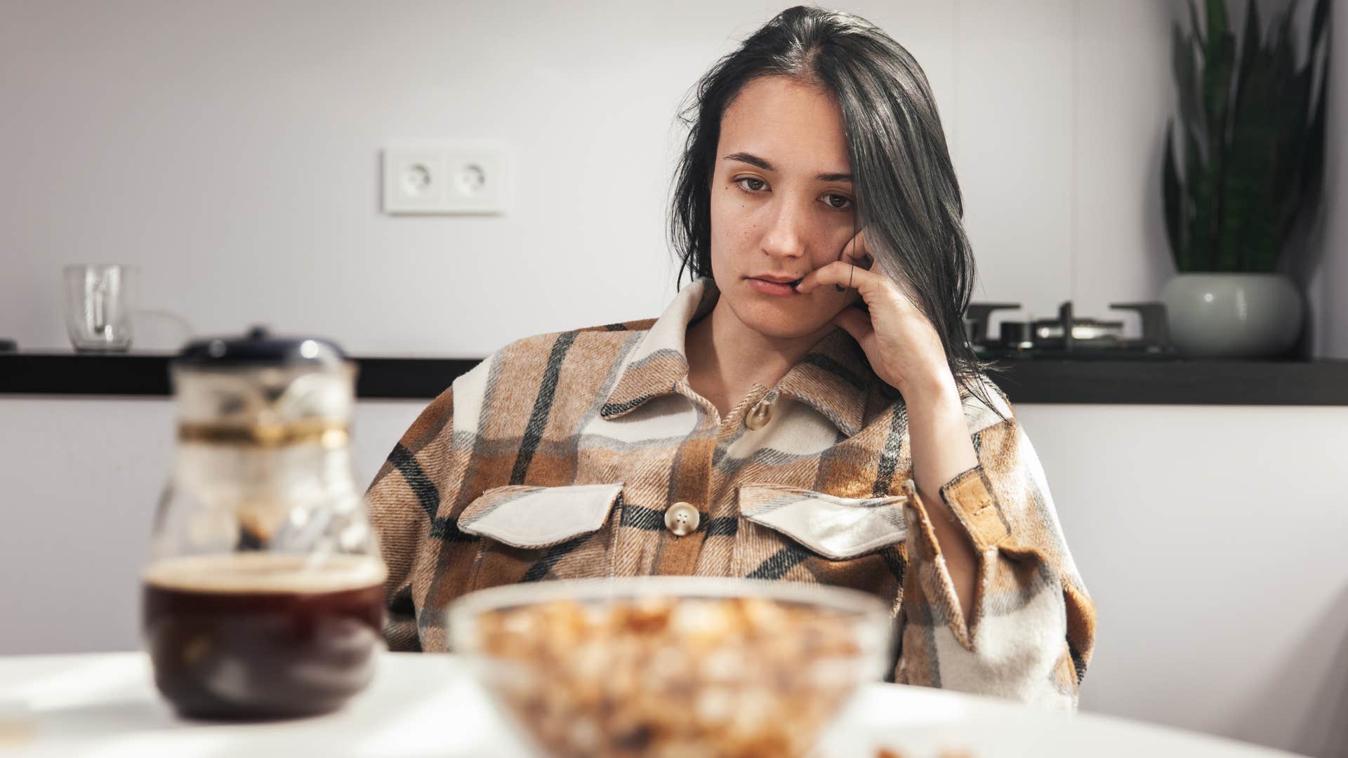 woman sitting by her overused coffee corner in the kitchen