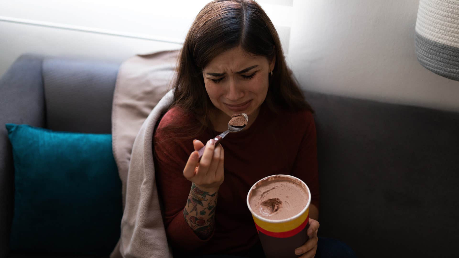 woman crying eating comfort food at home