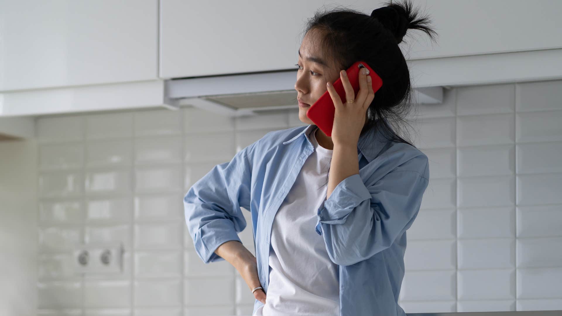 woman talking on the phone in her kitchen with bare walls
