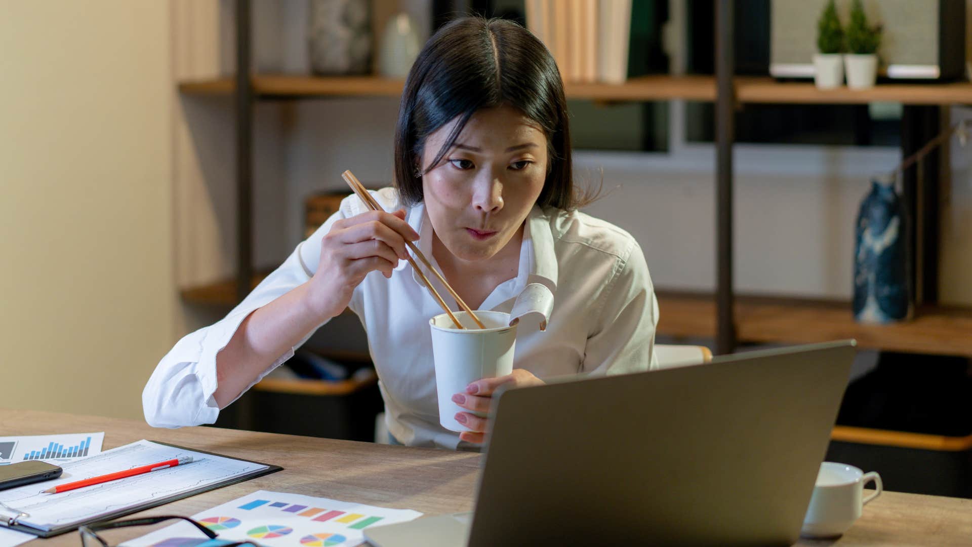 woman eating at home surrounded by remnants of take-out containers