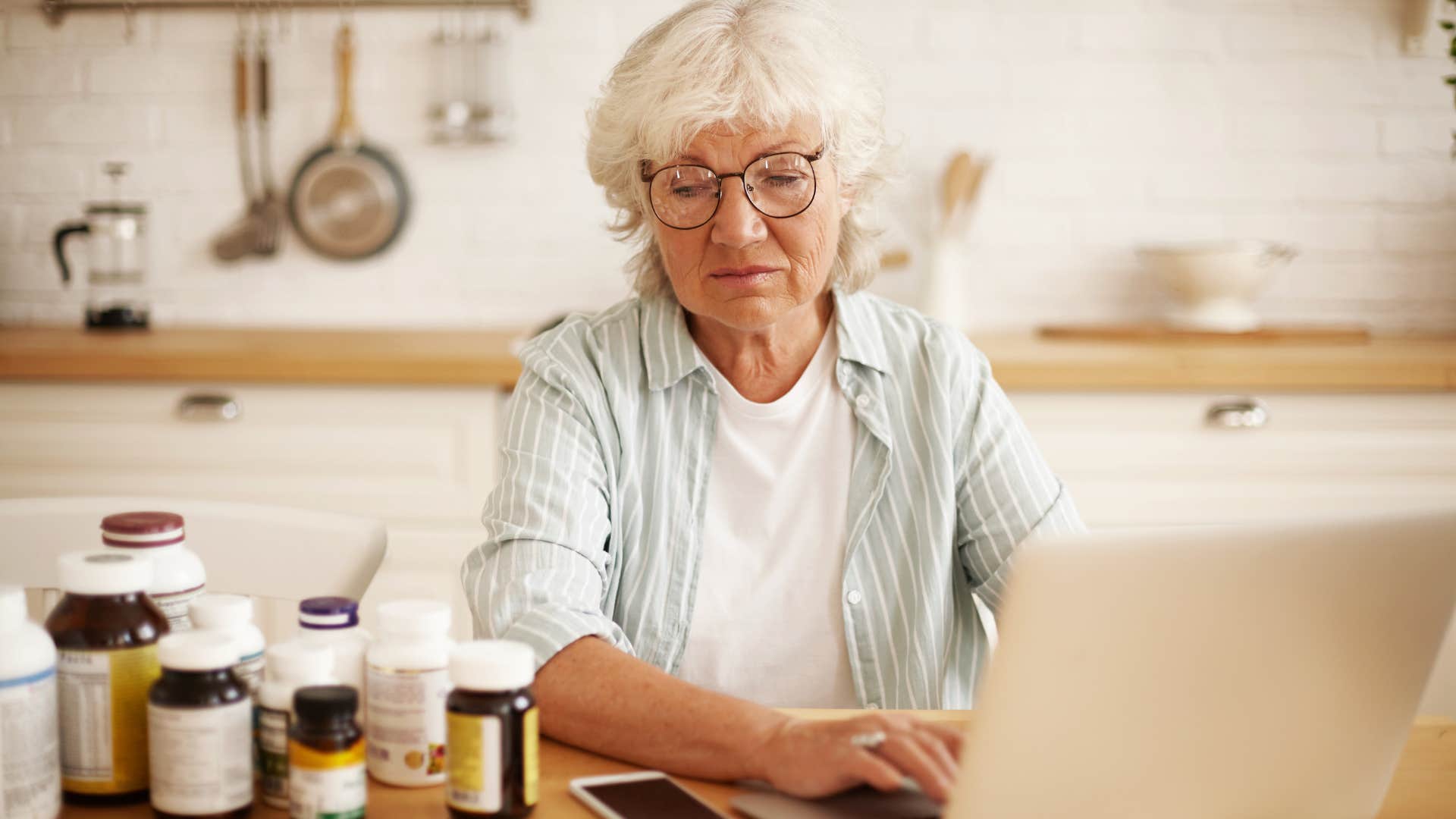 sad woman sitting in her kitchen next to unopened vitamins