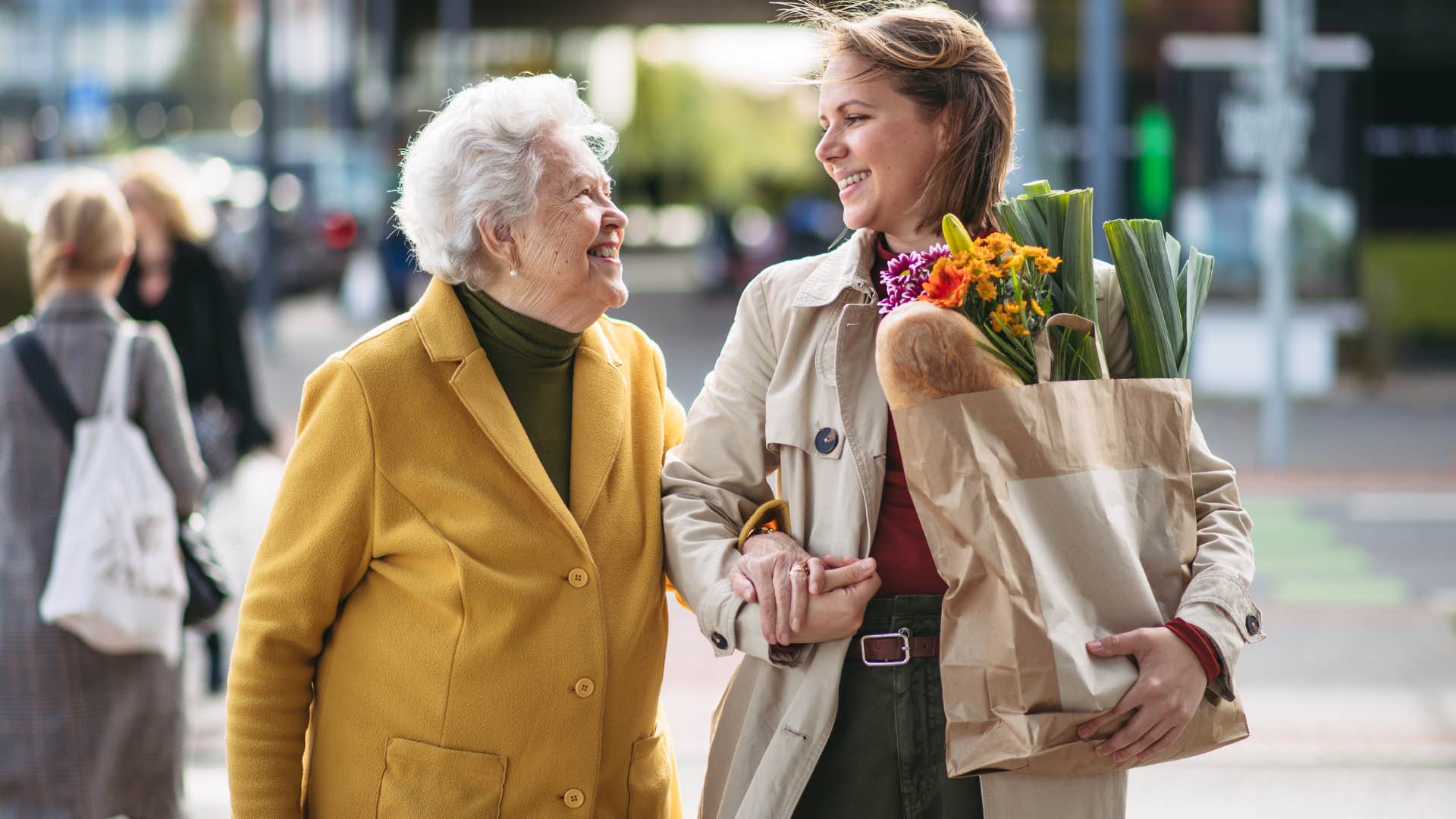 kind woman helping older woman with groceries in public