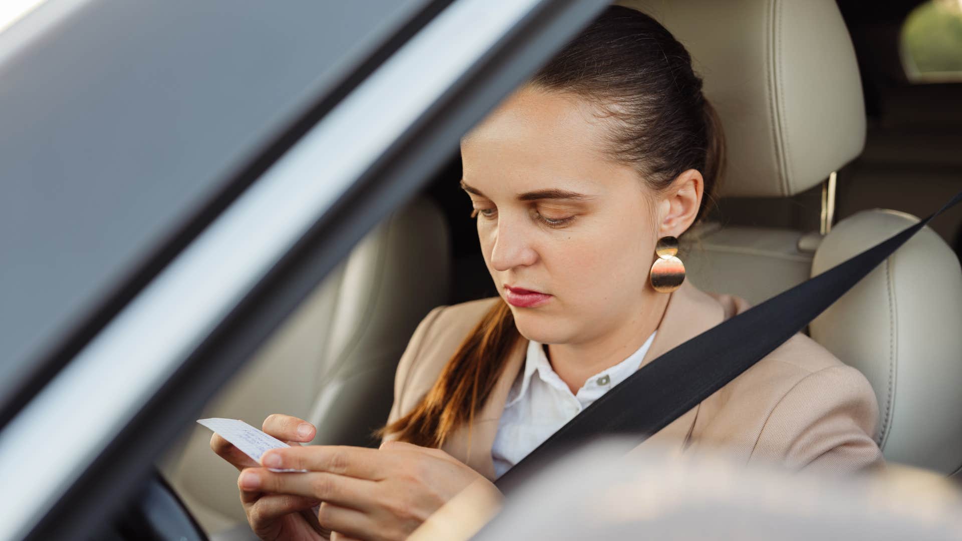 woman looking at expired coupon in car