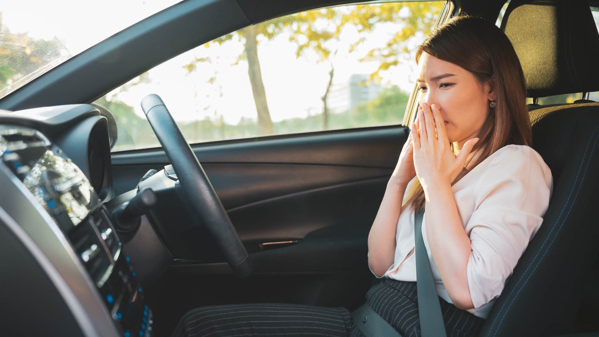 disgusted mom covering her nose sitting in car