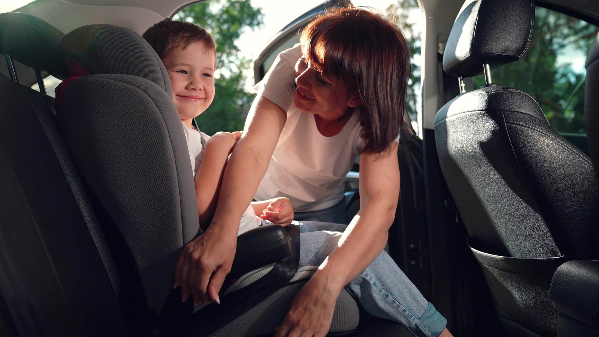 mom buckling up kid into carseat
