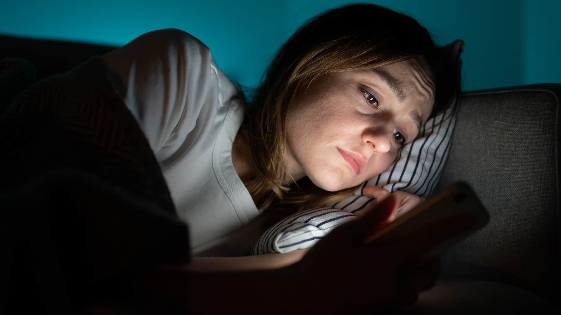 Woman looking at screens in the bedroom at home.