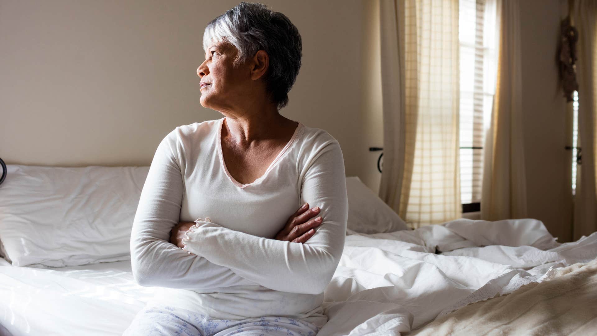 Woman sitting in her unmade bed at home.