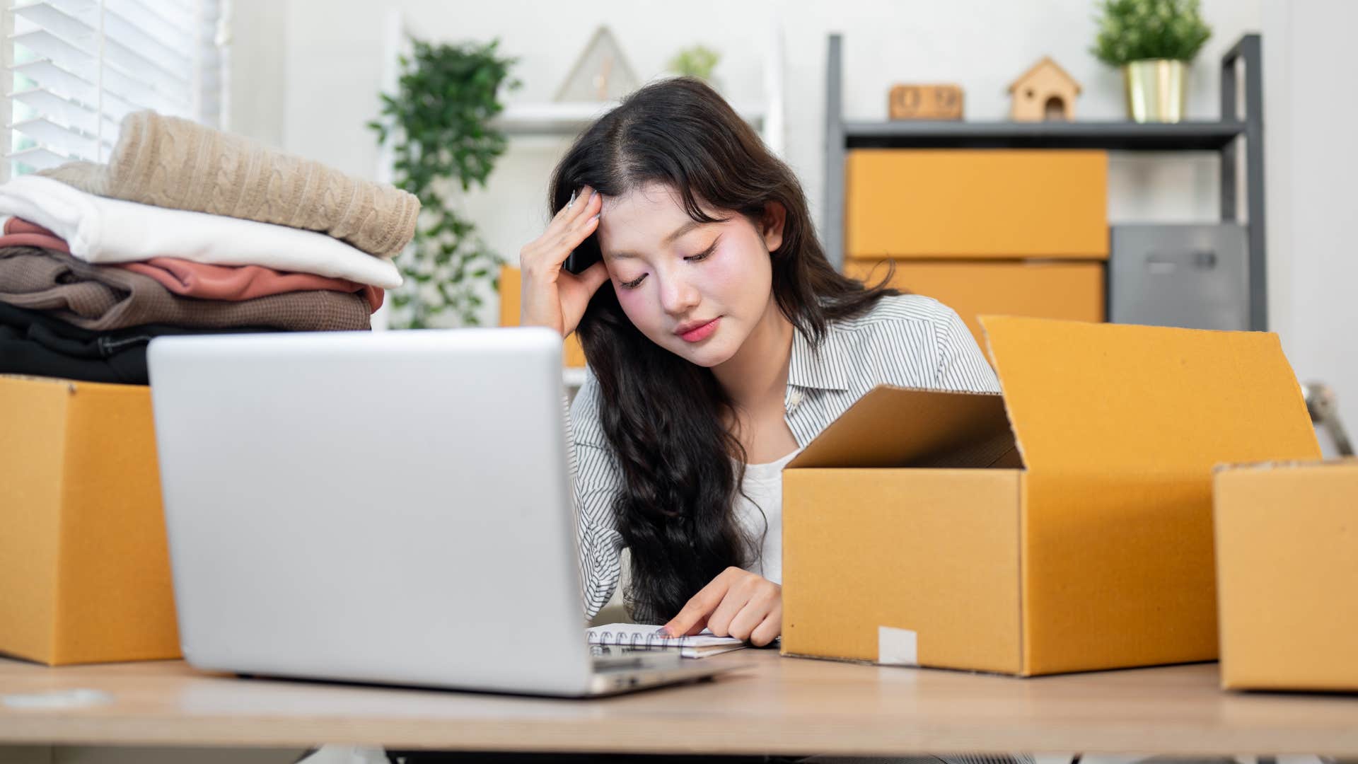 Woman sitting next to unopened mail and packages at home.