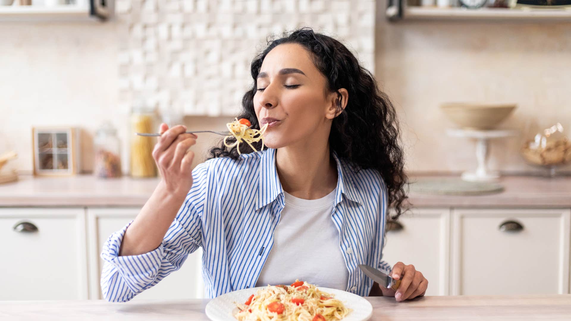 woman eating spaghetti dinner in kitchen