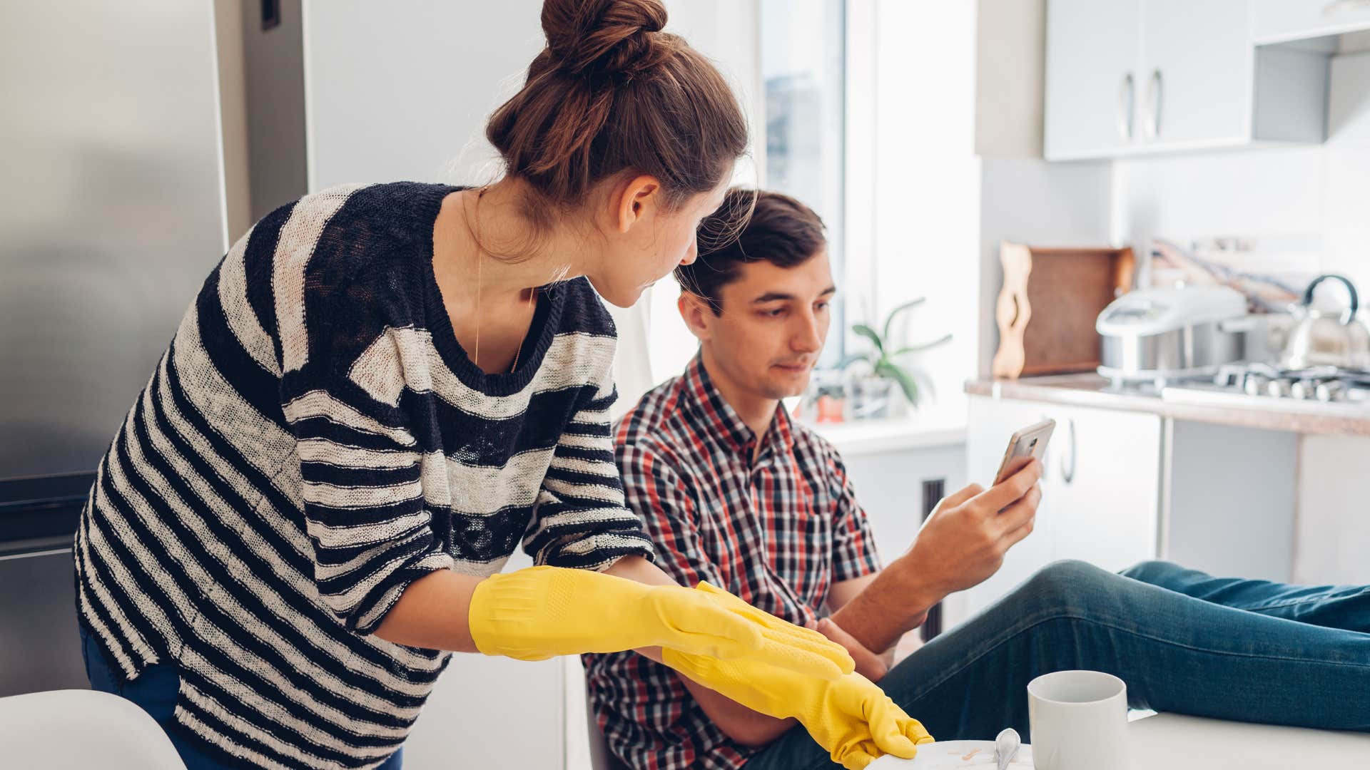 Woman cleaning next to her partner who's not offering to help.