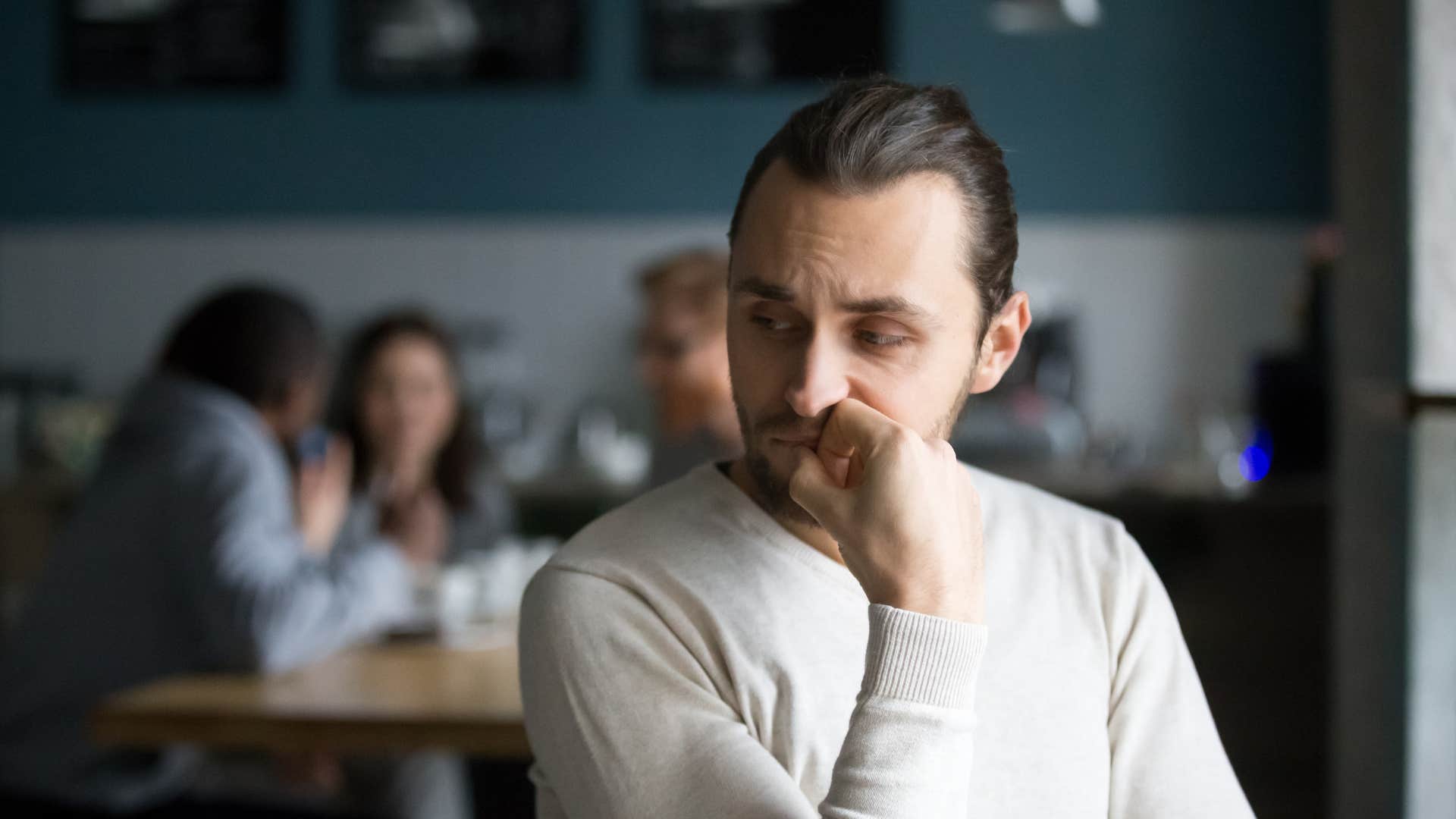 man upset sitting away from friends