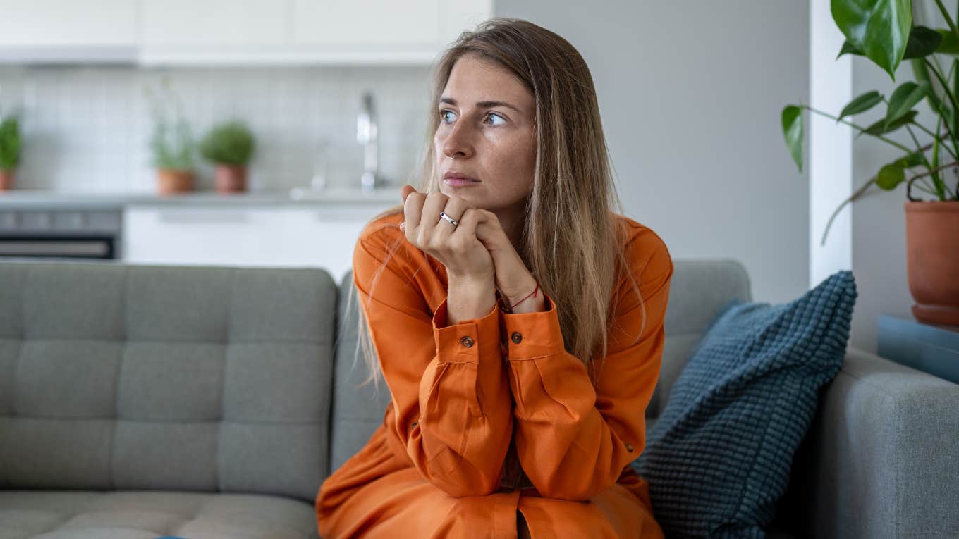 concerned woman looking around friend's house sitting on couch