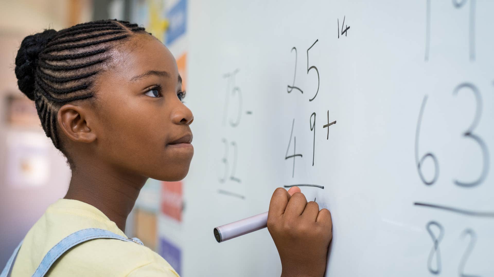 young girl doing math on the dry erase board