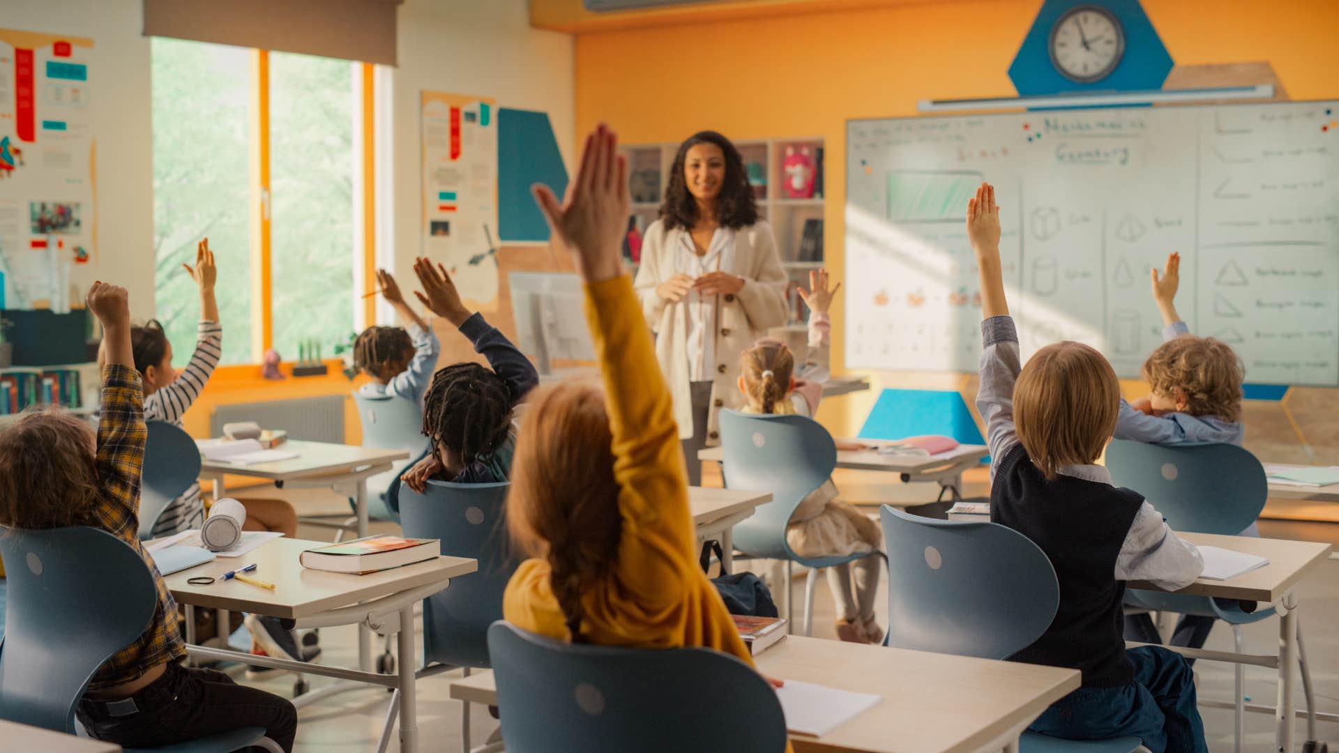 class of students raising their hands to answer teacher's question