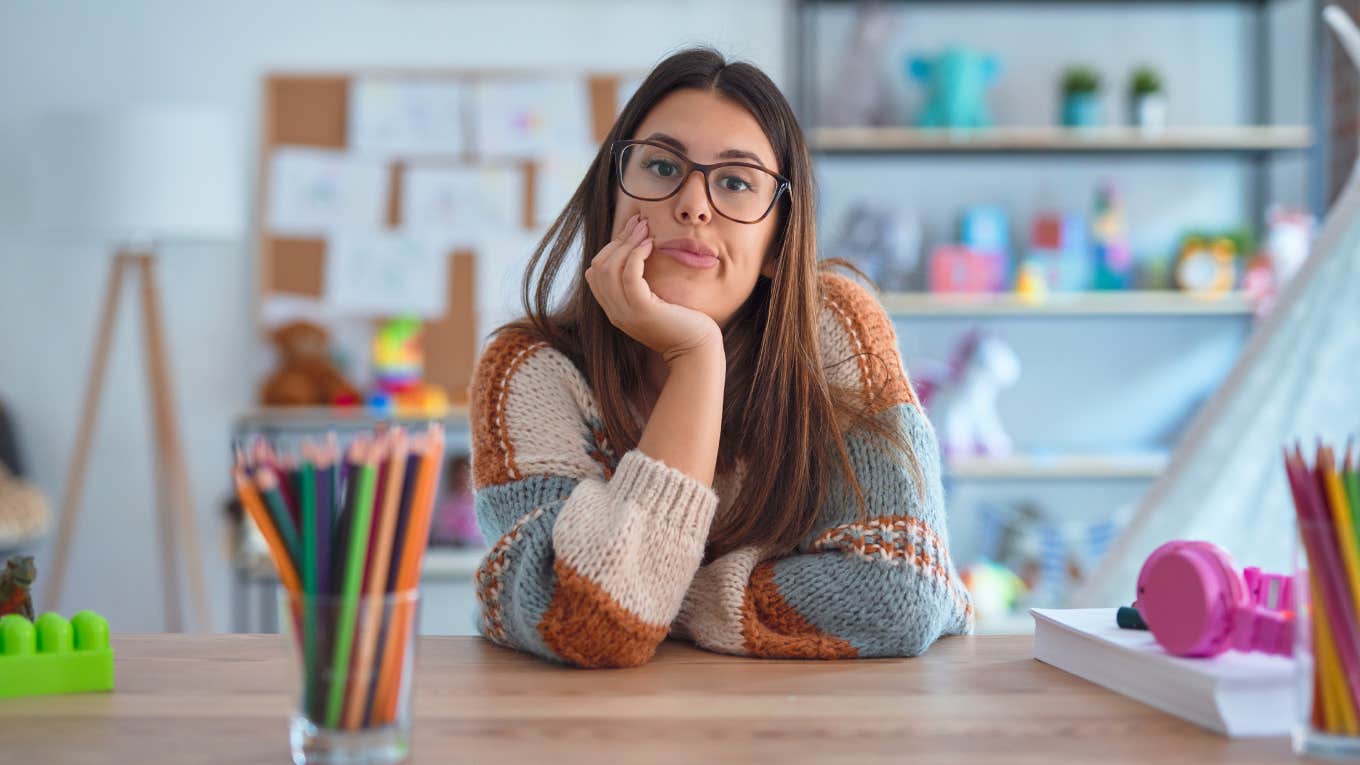Once-Passionate Teacher Now Hates Her Job Because The School System Leaves Students ‘Suffering’ stressed young teacher sitting at desk in classroom