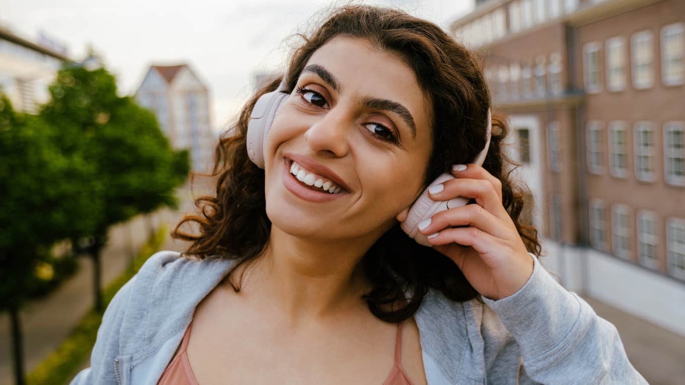 happy woman smiling while listening to music outdoors