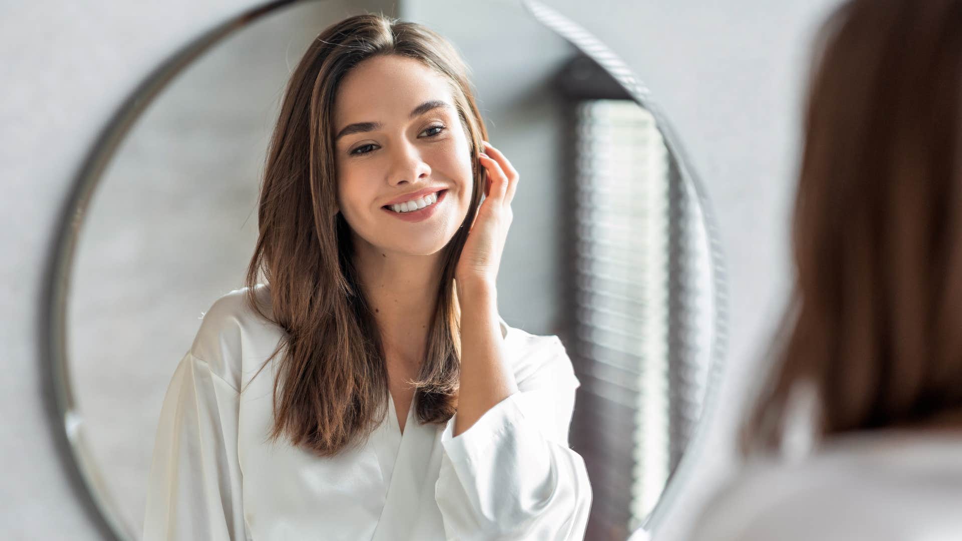 woman looking in mirror prioritizing self-care