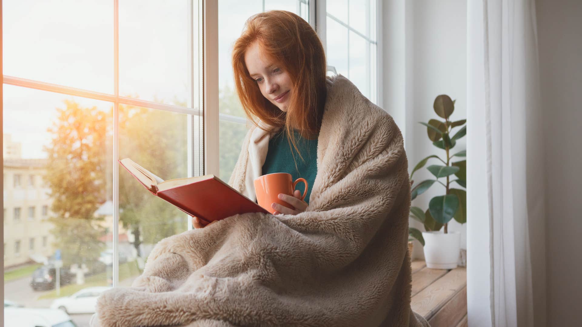 woman wrapped up in a blanket reading