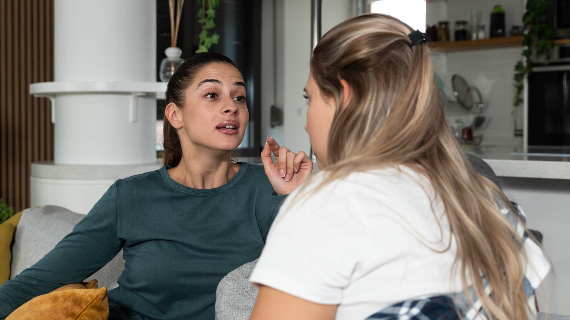 woman in green saying i was here first to woman in white on couch