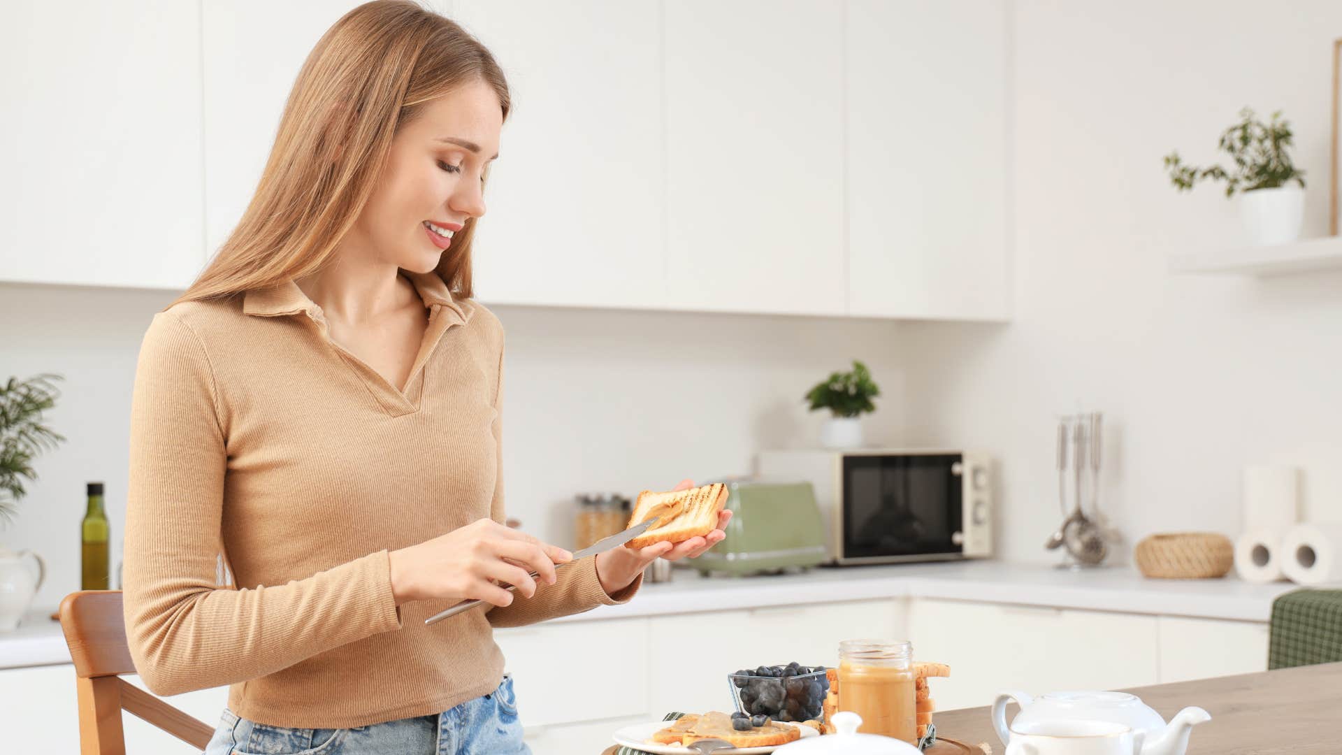 woman spreading butter from a dish on toast