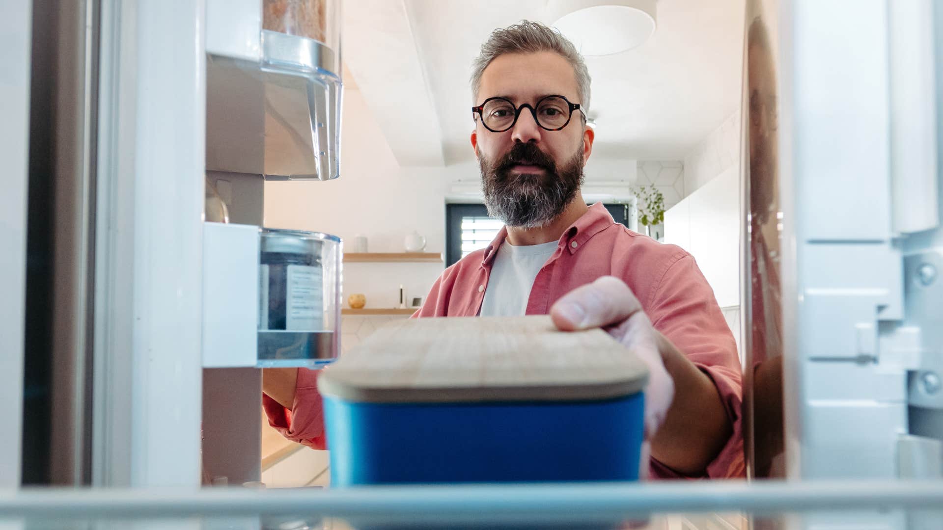 man taking food from fridge to put in garage freezer