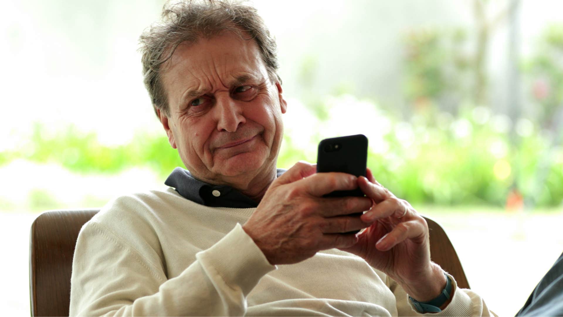 older man rolling his eyes at the fakeness of social media on his phone