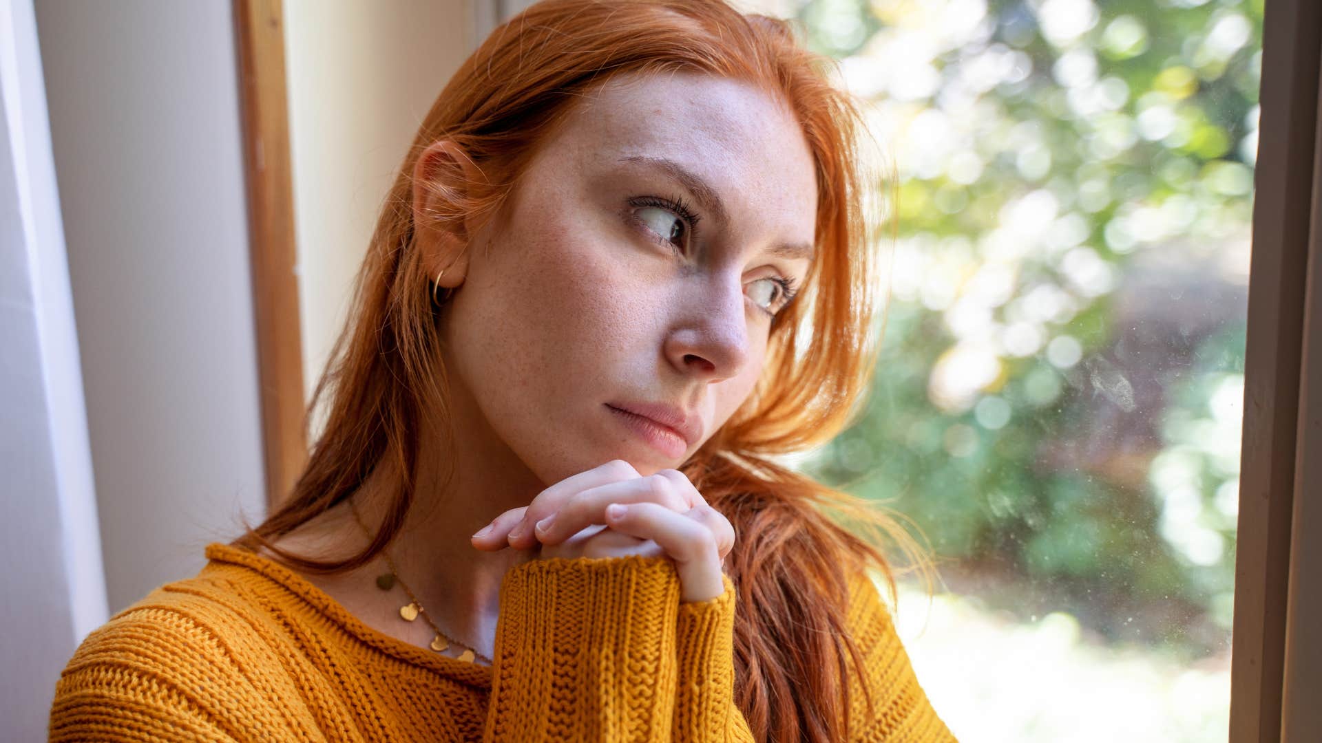 highly sensitive woman looking out the window thinking
