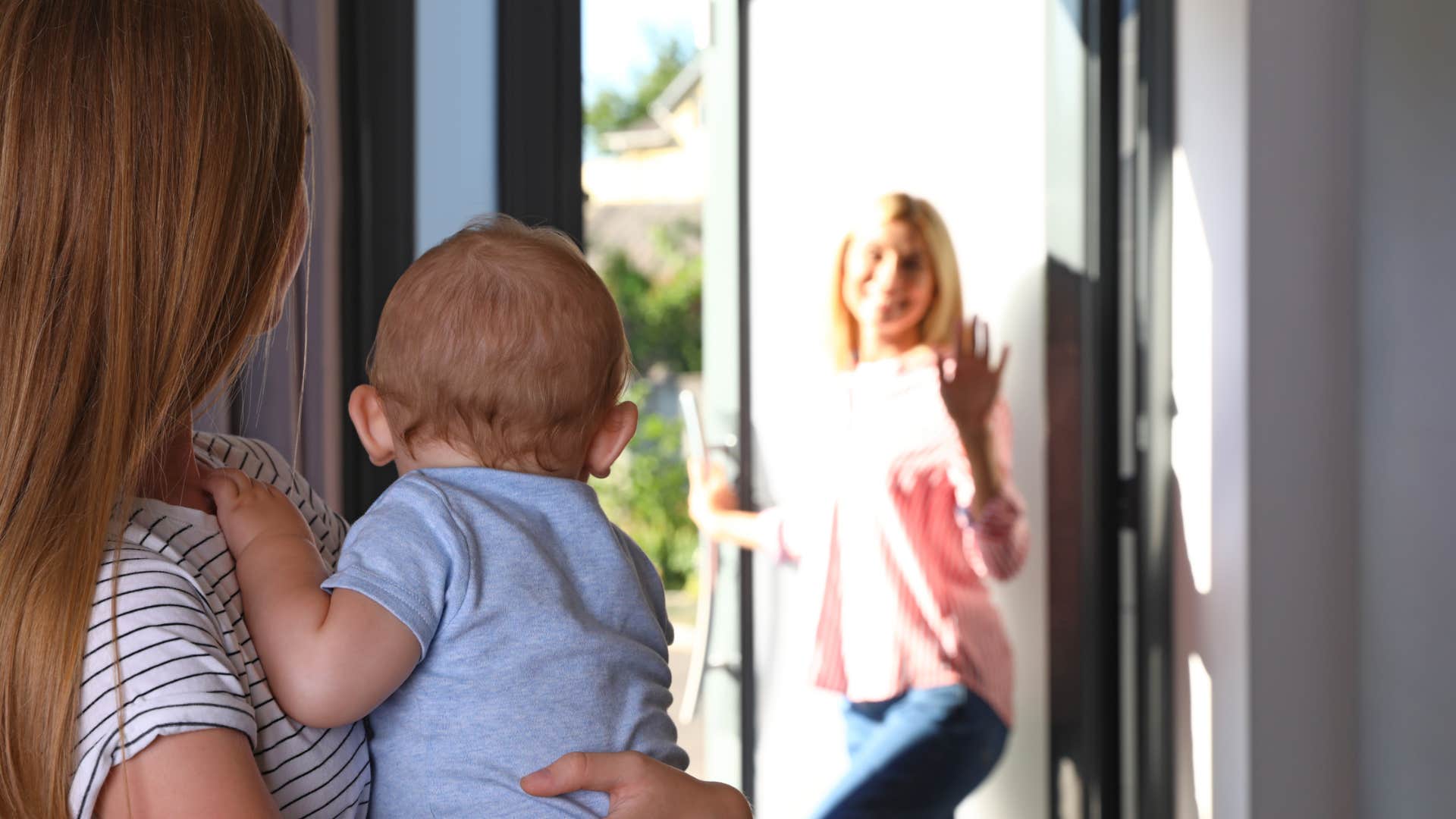 mom saying goodbye to babysitter holding her child